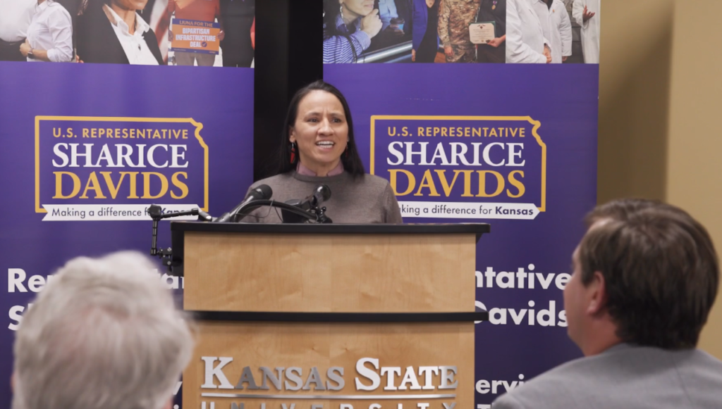 US House Representative for District #3 standing at a podium.